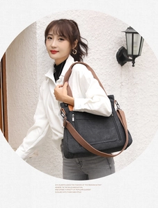 Deep grey canvas tote bag with brown wide strap shown on a model against a white wall