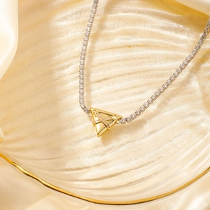 Close-up of golden triangle pendant with pavé cubic zirconia on a tennis chain