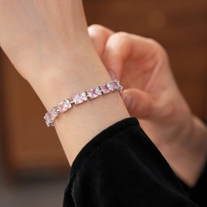 Primer plano de pulsera de tenis con circonitas rosas en la muñeca acabado plateado