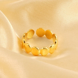 Détail macro d'une bague ajustable dorée avec texture de coquillage sur du satin