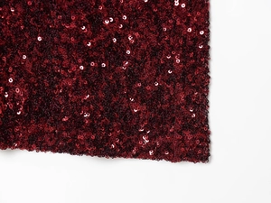 Detailed macro view of burgundy sequin fabric texture for an elegant evening gown
