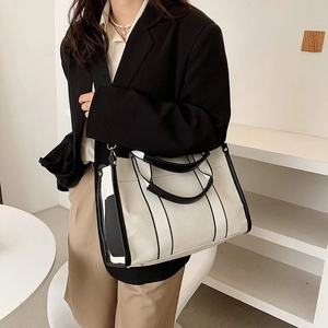Minimalist canvas tote bag with black and white contrast design and wide shoulder strap