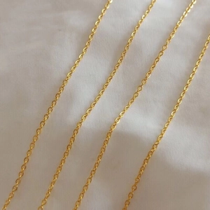Classic gold titanium steel cable chain necklace laid on white fabric background