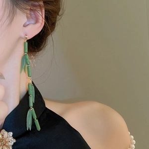 Detail of green resin bamboo joint earrings on Asian model wearing classic Chinese attire