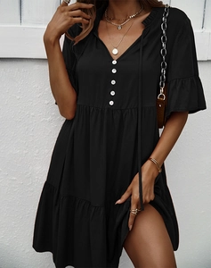 Détail d'une robe d'été noire à col en V avec boutons blancs et jupe à volants étagés