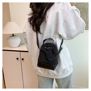 Model wearing a black canvas drawstring crossbody bucket bag from a back view perspective