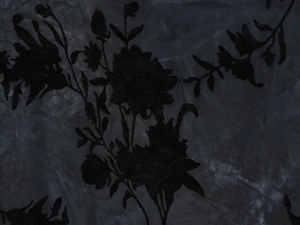 Dettaglio macro del tessuto in velluto dévoré nero con elegante floccaggio floreale e velo