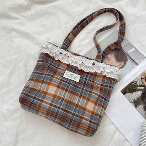 Close-up of vintage plaid tote bag featuring white lace trim and happy label detail