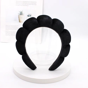 Detail of a thick black velvet padded headband with elegant cloud pleats on a white stand