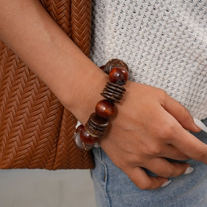 Close-up of bohemian brown wood beads and coconut shell bracelet on model's wrist