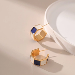 Detail of gold C-shaped hoop earrings with alternating blue and white enamel inlay