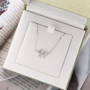 Macro shot of silver leaf pendant with marquise-cut stones in a green jewelry gift box