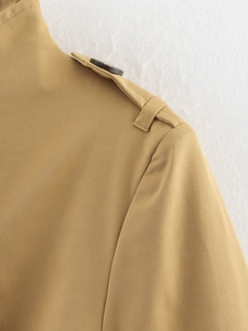 Detail der khakifarbenen Trenchcoat-Schulter mit Schulterklappe und dunklem Knopf