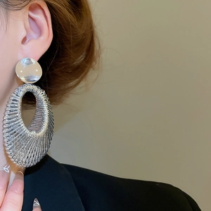 Gros plan détaillé des boucles d'oreilles créoles ovales en métal argenté tressé