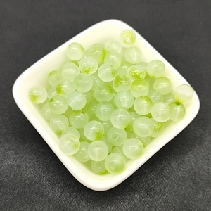 Detailed close-up of 8mm round translucent light green glass beads in a white bowl