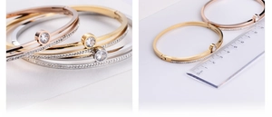 Detail view of hollow gold bangles with paved rhinestones being measured for 6cm size
