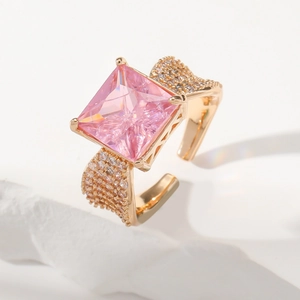 Macro detail of gold ring featuring a large pink square gemstone and pave set side stones