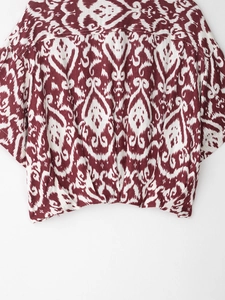Close-up of red and white Ikat print fabric showing natural linen texture on a shirt