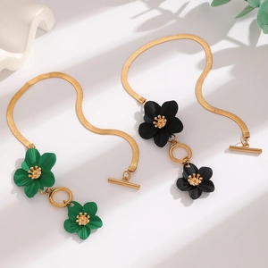 Detail of Y-shaped necklaces featuring green and black floral pendants with gold chains