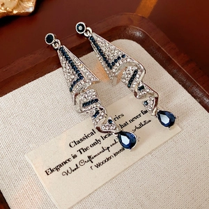 Close-up of elegant silver drop earrings with blue crystal set on a wooden tray