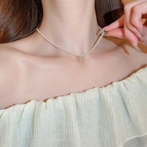 Gros plan sur l'élégant collier de perles avec un pendentif strass étincelant sur modèle
