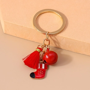 Detail of Christmas keychain with red bell, tassel and snowflake stocking on gold ring