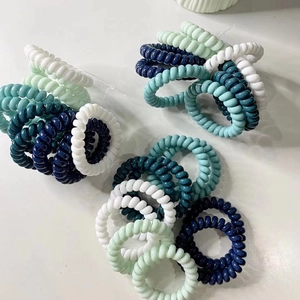 Close-up of flexible spiral phone cord hair ties in blue, green, and white colors