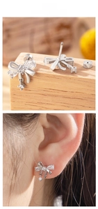 Detail of silver bow earrings with marquise cubic zirconia and star charm pendants