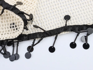 Detail aus weißem Netzstoff mit schwarzem Band und Paillettenfransen für Kleider