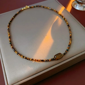 Macro detail of tiger eye beaded necklace with gold spacers on a jewelry display stand