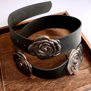 Gros plan d'une ceinture en cuir noir avec trois boucles de roses en métal argenté