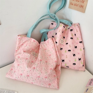 Detailed view of pink floral canvas shoulder bags with blue handles and cat patterns