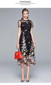 Close-up of black mesh dress featuring intricate pink, yellow and blue floral embroidery