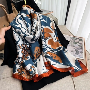 Detailed view of long silk scarf with blue and orange floral prints on black clothes