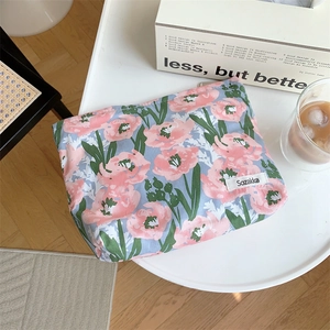 Detailed top view of a floral cotton makeup bag on a desk with lifestyle accessories