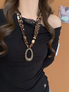 Detail of leopard print fabric strap and translucent amber resin pendant on long necklace