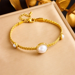 Detailed view of a gold pearl bracelet with sparkling diamonds on a beige display mat