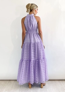 Back view of a tiered purple checkered maxi dress with halter neck and ruffled hemline