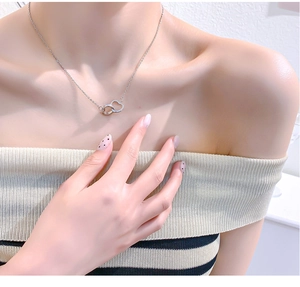 Close-up of double heart pendant necklace in silver with pavé crystal accents on model