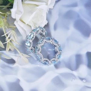 Close-up of pavé micro-set light blue gemstone earrings with elegant white roses