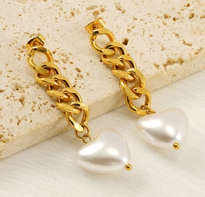Detailed view of 18K gold chain earrings with white heart-shaped pearls on a stone background