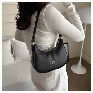 Detail shot of the black crescent underarm bag showing PU leather texture and bow accent