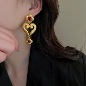 Nahaufnahme der goldenen Barock Herz Ohrringe mit roten Steinen und gehämmertem Finish.