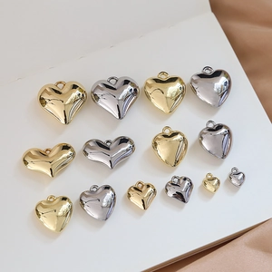 Flat lay of multiple sizes of gold and silver heart pendants on white book pages