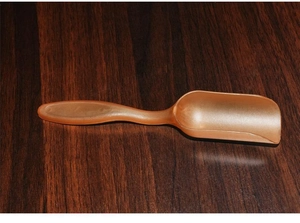 Detailed close-up of a long-handle light brown plastic scoop for tea or powder measurement