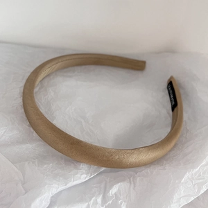Detailed view of beige satin headband on white paper with a handmade label inside