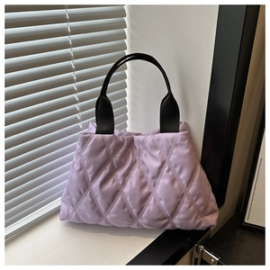 Close-up of purple quilted puffer tote bag with black strap and soft padded texture