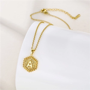 Detailed macro view of gold hexagonal pendant featuring letter A on a fine chain necklace