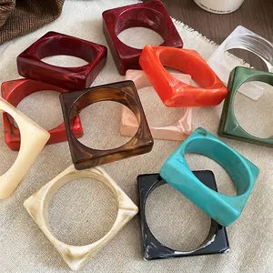 Colorful square acrylic resin bangles with marbled texture on natural linen fabric background