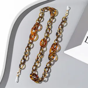 Detail of amber tortoiseshell acrylic eyewear chain with golden lobster clasps on tray